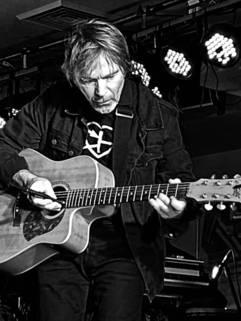 Roger Mason playing an acoustic guitar in black and white