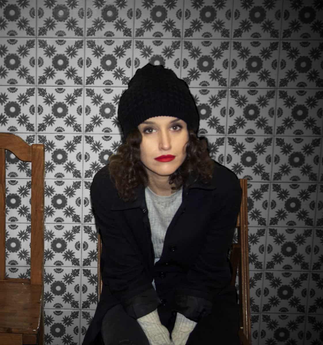 Steph Copeland sits against a wallpapered background