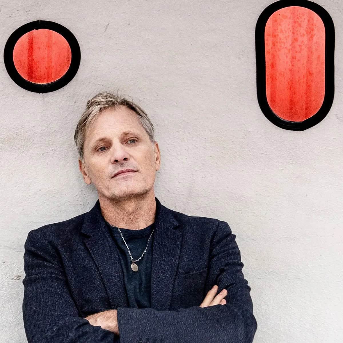 Viggo Mortensen Leans Against a White Wall